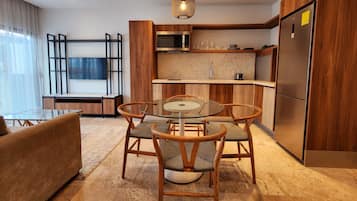Une cuisine moderne avec des meubles en bois, un four à micro-ondes encastré et un réfrigérateur en acier inoxydable.