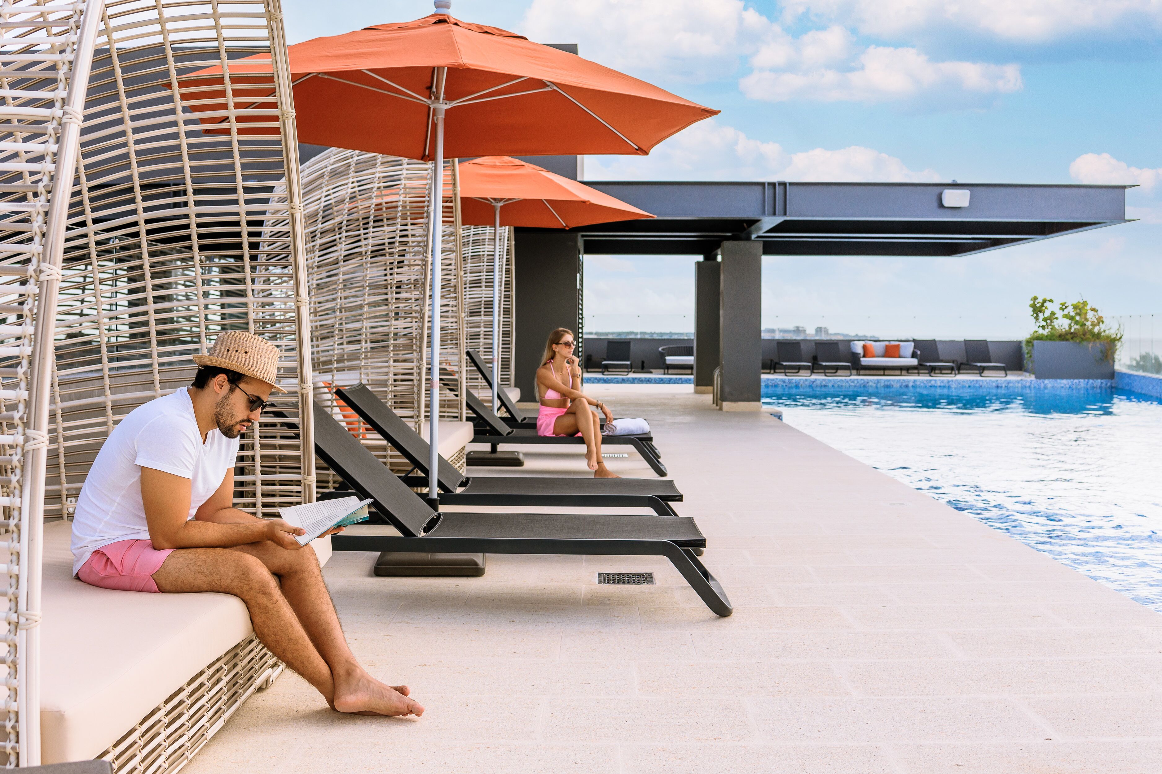 Ein Poolbereich mit Liegestühlen, Sonnenschirmen und Blick auf den Pool.