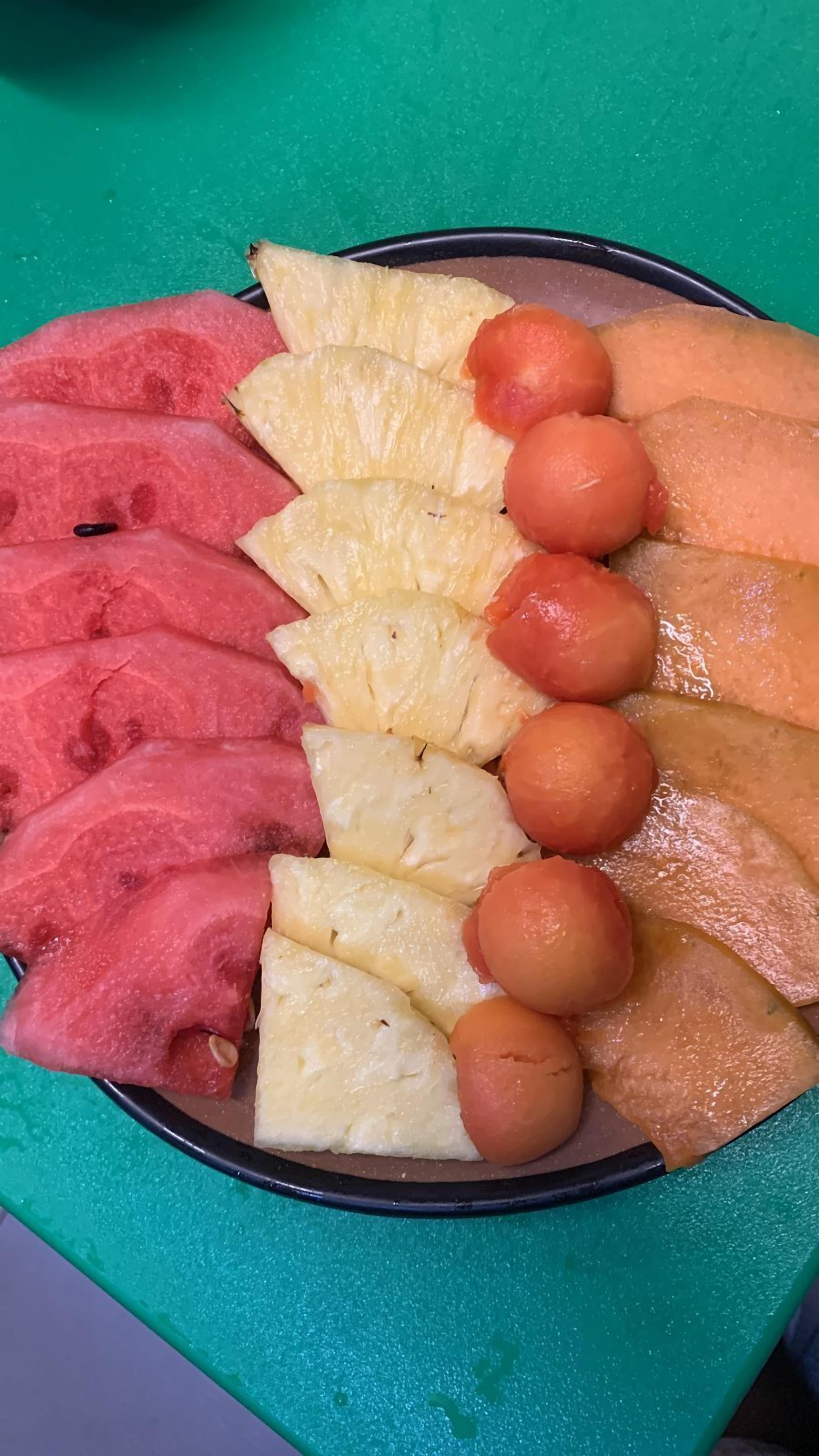 Ein Teller mit geschnittenem Obst, darunter Wassermelone, Ananas und Cantaloupe.