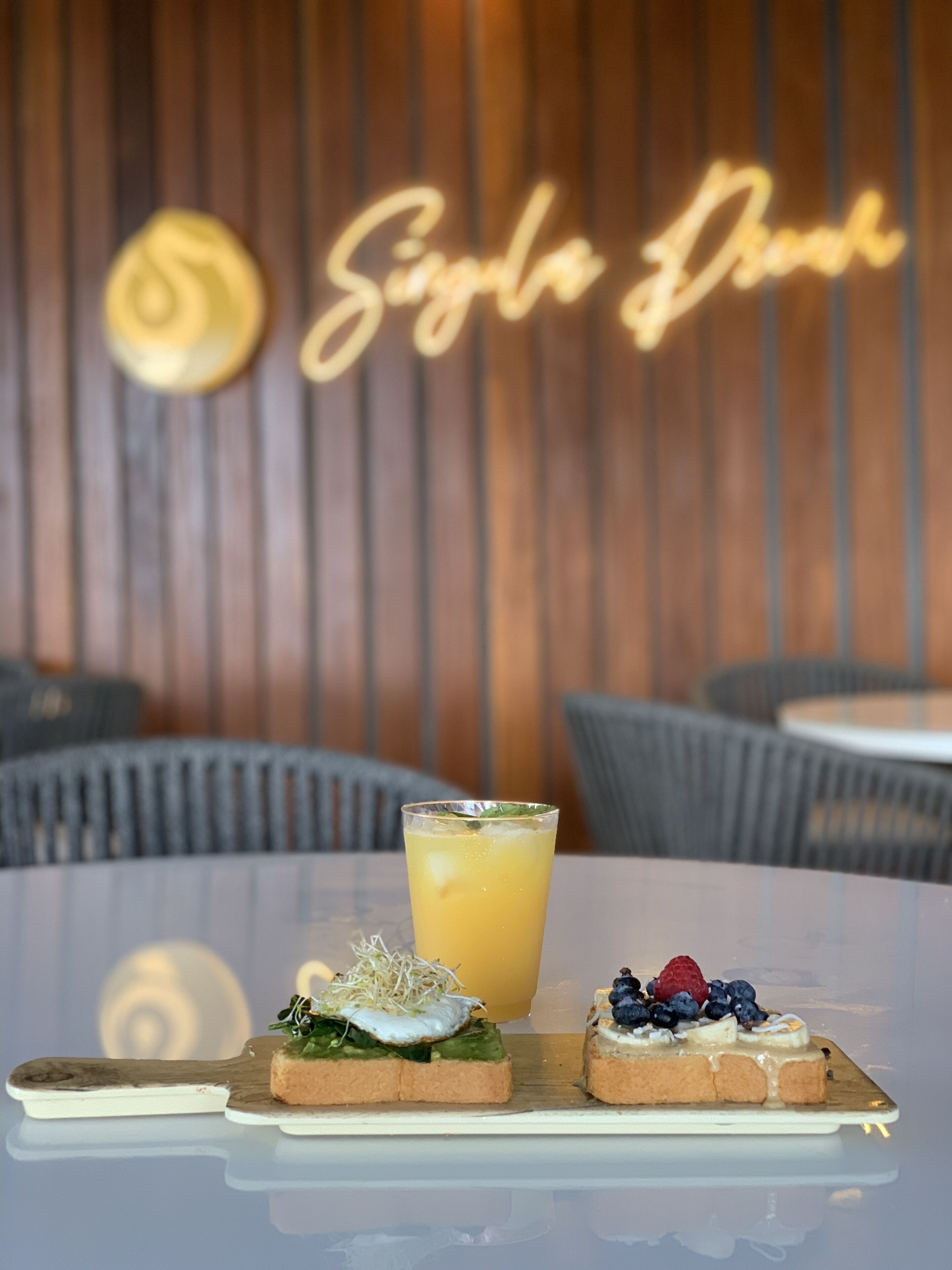 A table with two small dishes of food and a glass of drink in a restaurant setting.