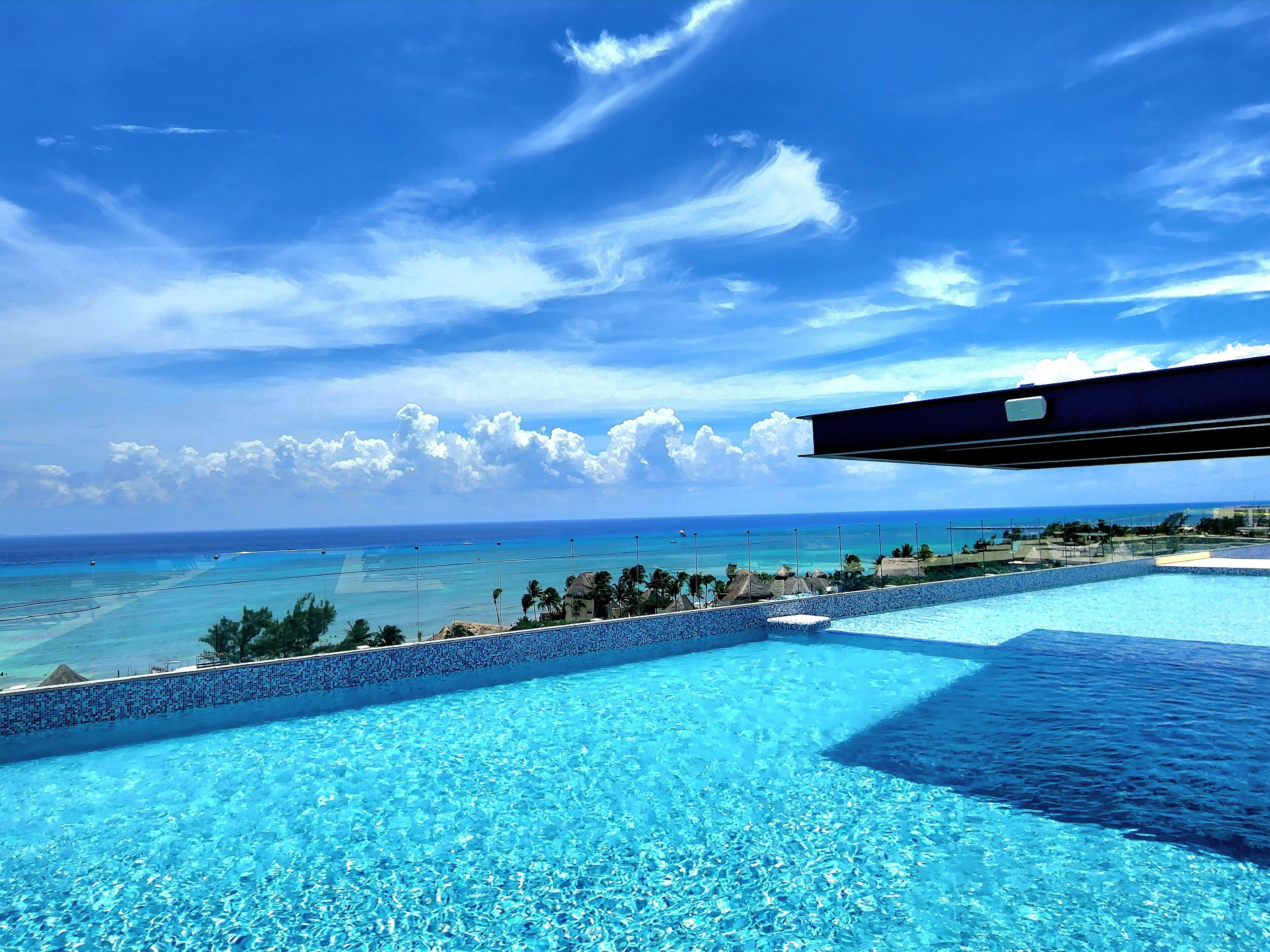A clear blue sky, a swimming pool, and a view of the ocean.