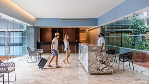 A modern lobby with a marble reception desk, glass walls, and seating areas. - Singular Dream Beach Residences (Playa del Carmen)