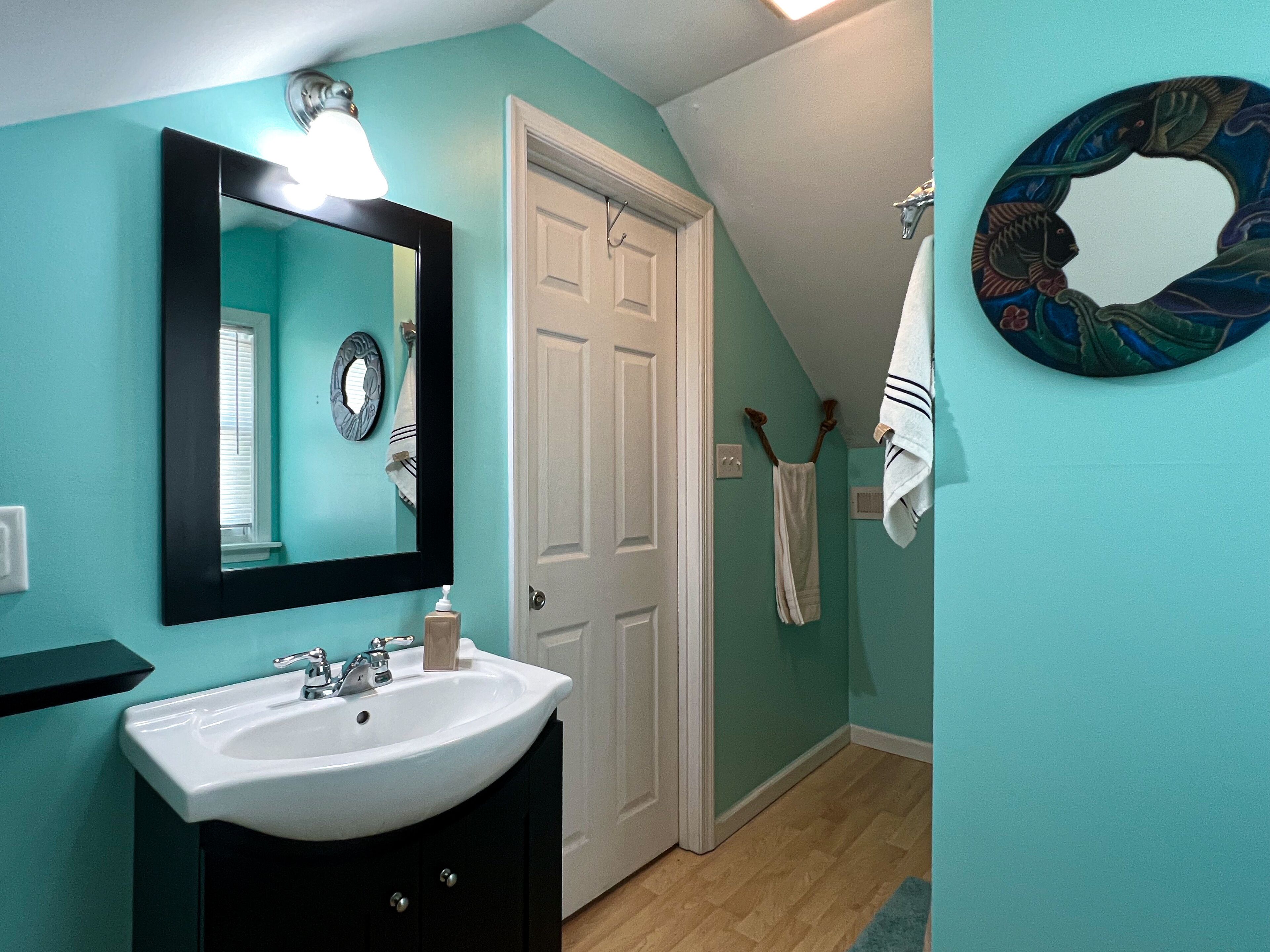 Une salle de bain avec un lavabo blanc, un miroir et une porte.