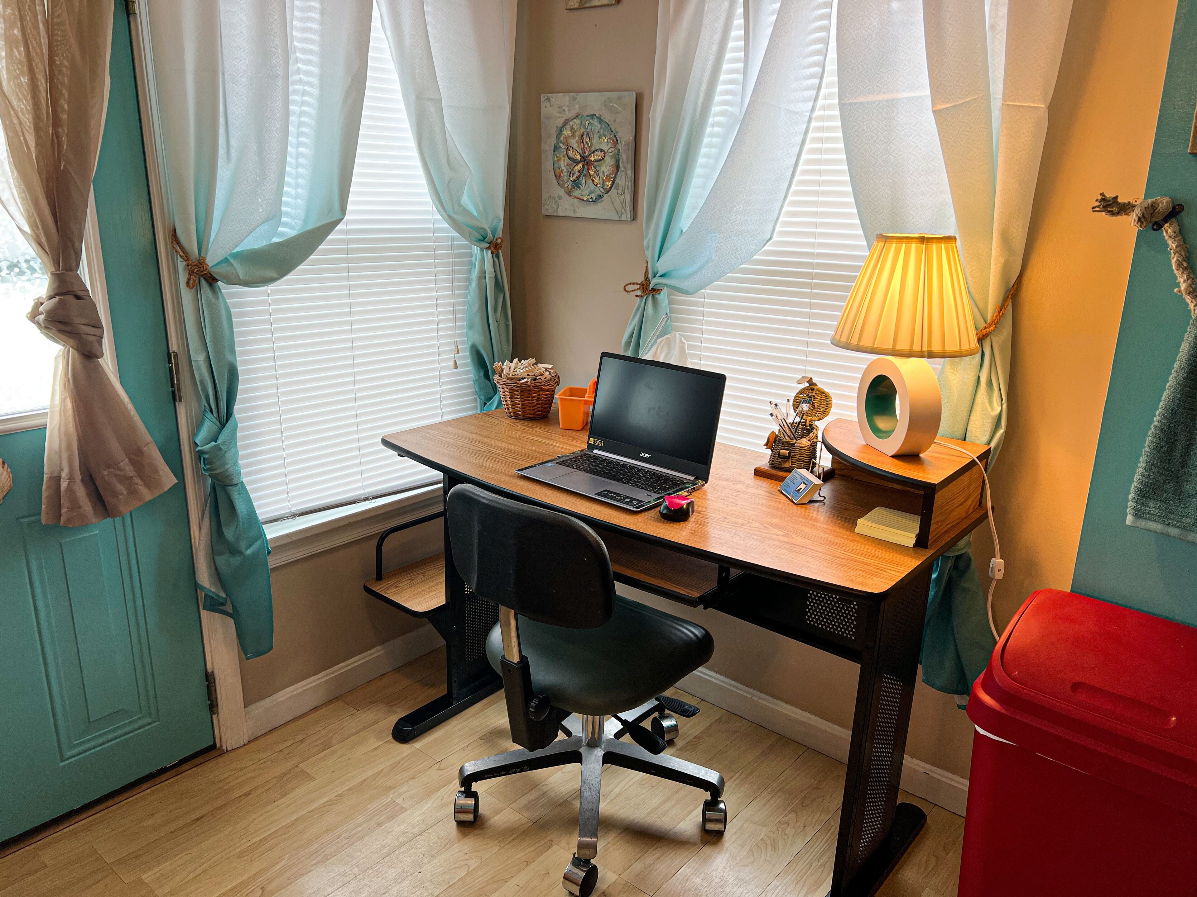 Un espacio de oficina ordenado con un escritorio de madera, una computadora portátil, una silla y una lámpara.