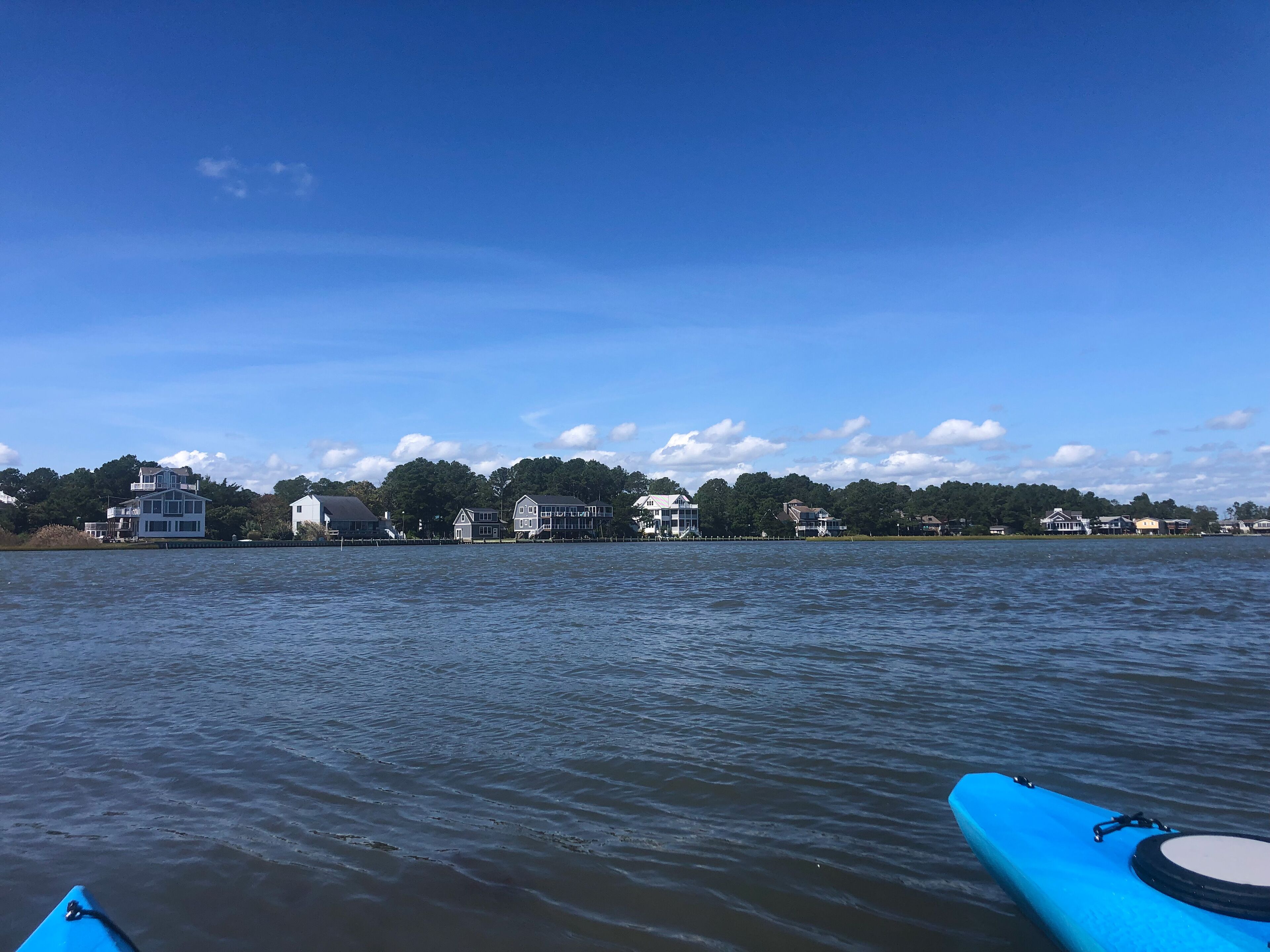 A waterfront view with houses along the shore and a calm body of water.