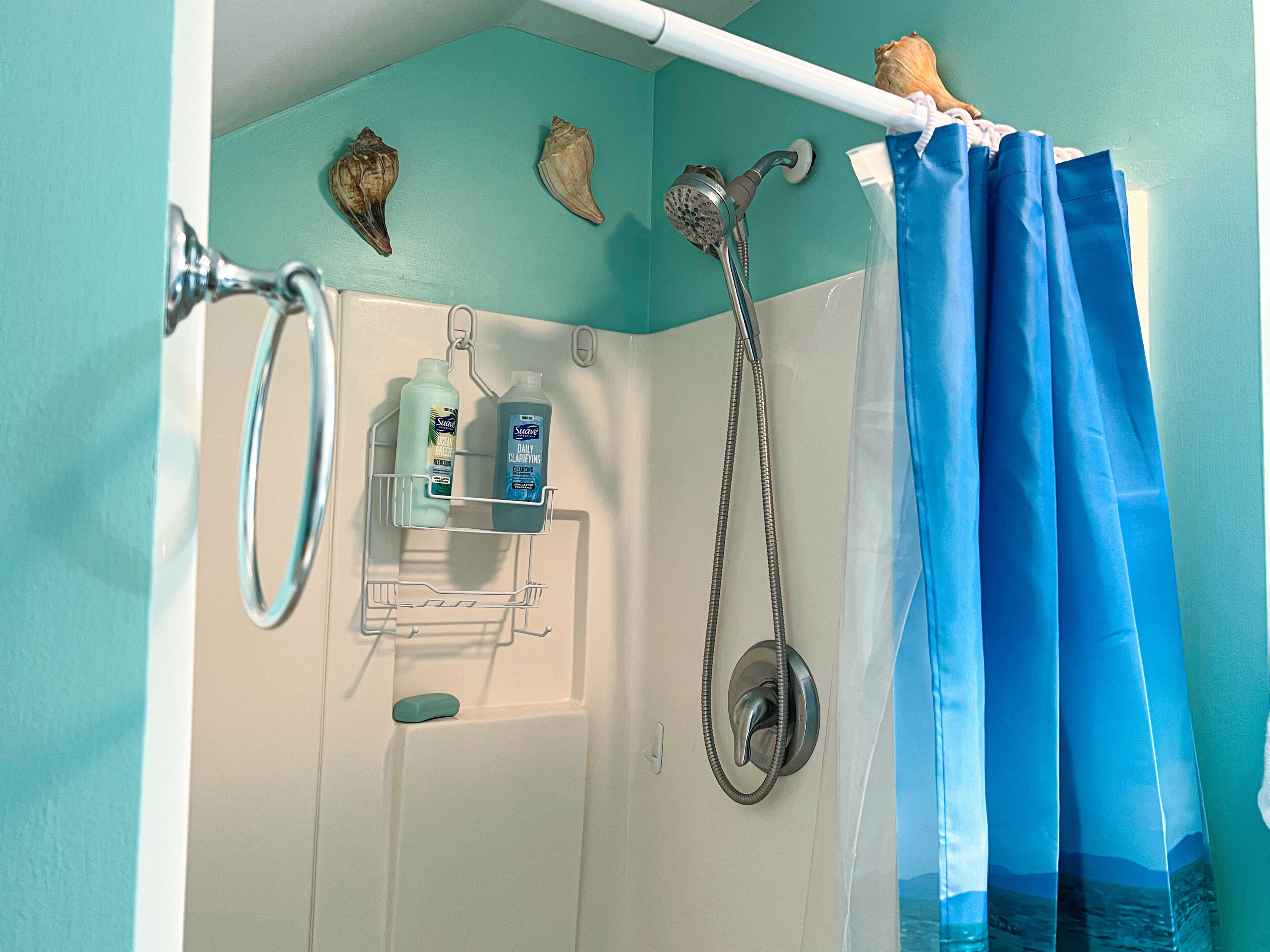 A bathroom with a shower, a towel rack, and a shelf with toiletries.