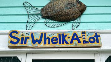 Un objet décoratif en forme de poisson et une enseigne sur laquelle on peut lire « SirWhelkA’lot ».