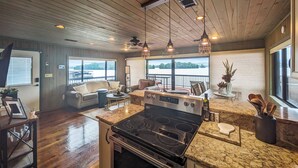 Cucina spaziosa con isola centrale ampia, soffitto in legno e vista su un lago.