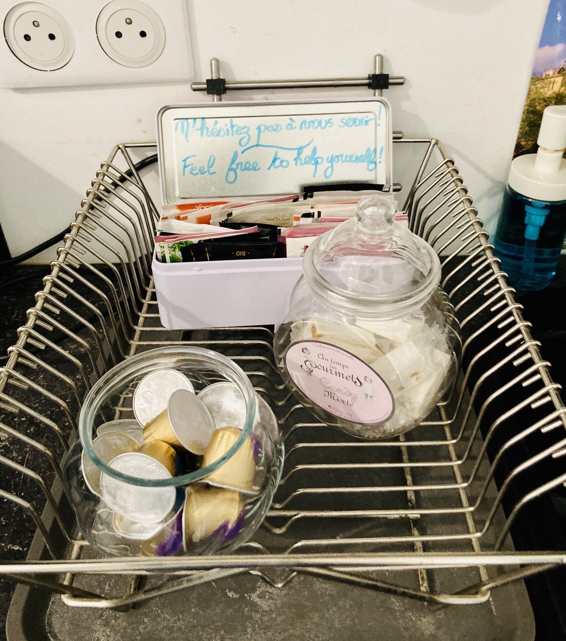 Un panier en métal avec une pancarte, un bocal en verre avec une étiquette et un récipient en plastique avec un couvercle.