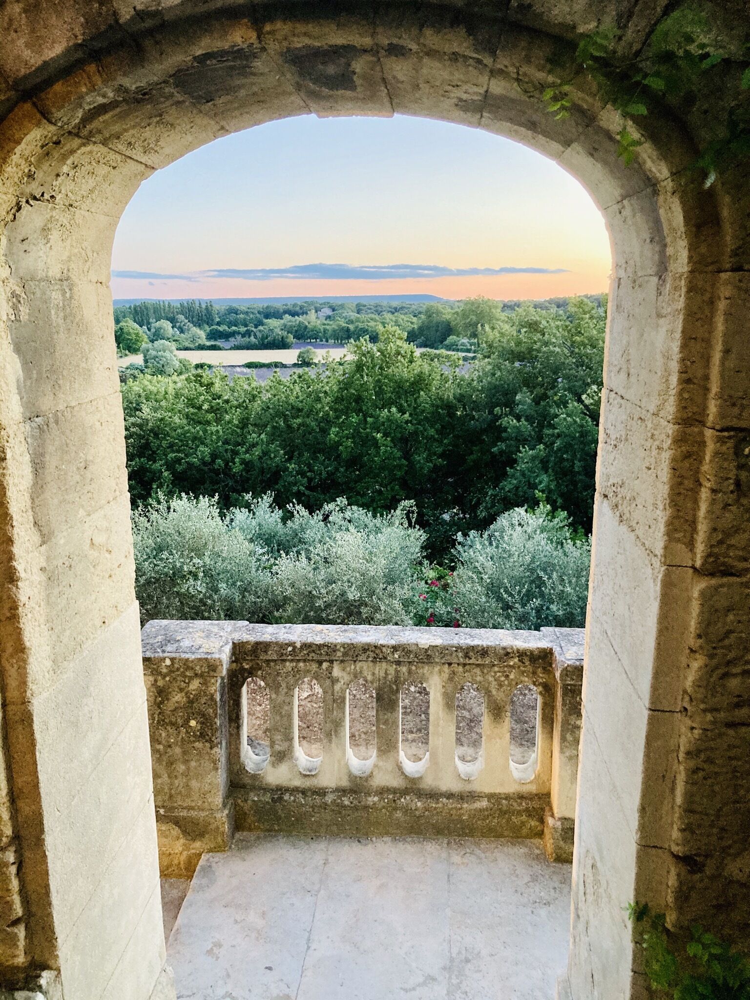 An arched stone structure with a view of a green landscape.