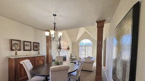 A dining area with a round table, four chairs, a chandelier, and a fireplace. - The Erie Home: Warm and Spacious in South Tulsa (Tulsa)