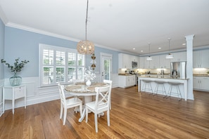 A spacious kitchen with wooden flooring, white cabinetry, and a central island with bar stools.