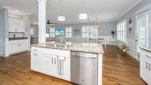 A spacious kitchen with white cabinetry, a granite countertop, and a built-in dishwasher. - Kappi’s Luxury Coastal Retreat (North Charleston)