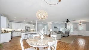 A spacious living area with a round dining table, white chairs, a sofa, and a ceiling fan. - Kappi’s Luxury Coastal Retreat (North Charleston)