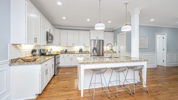A modern kitchen with white cabinetry, granite countertops, stainless steel appliances, and a central island with bar stools. - Kappi’s Luxury Coastal Retreat (North Charleston)