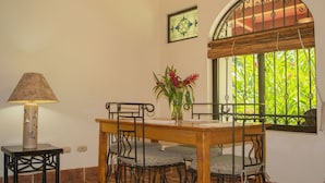 Un coin repas comprenant une table, des chaises, une lampe et une fenêtre donnant sur un paysage verdoyant.