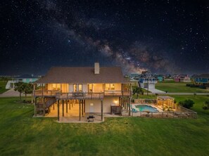 A two-story house with a balcony, a swimming pool, and a well-maintained lawn. - Secluded Getaway with Pool and Game Room (Galveston)