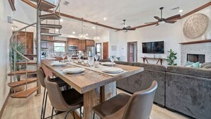 A spacious kitchen with a central island, a spiral staircase, and a dining area with a long table set for six. - Secluded Getaway with Pool and Game Room (Galveston)