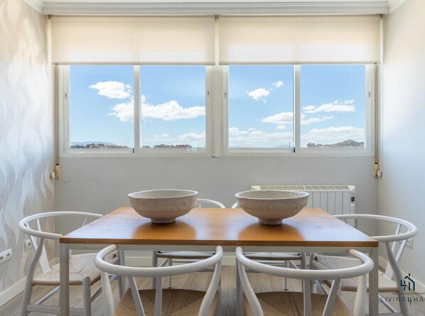 Enjoy meals in this cozy dining area with a table and chairs, overlooking a view of the city.