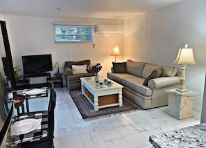 Relax in this stylish living room with a comfortable sofa, flat-screen TV, and dining area.
