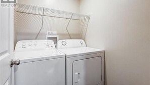 Une buanderie équipée de deux machines à laver à chargement frontal, de couleur blanche, et d’un étendoir.