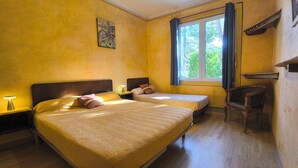 Une chambre avec deux lits, une fenêtre avec des rideaux, une œuvre d’art accrochée au mur et une chaise en bois.
