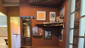 Une pièce avec un sol carrelé, un banc en bois, une étagère remplie de livres et un tableau encadré accroché au mur.