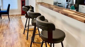 Een moderne keuken met een houten aanrecht, barstoelen en een roestvrijstalen koelkast.