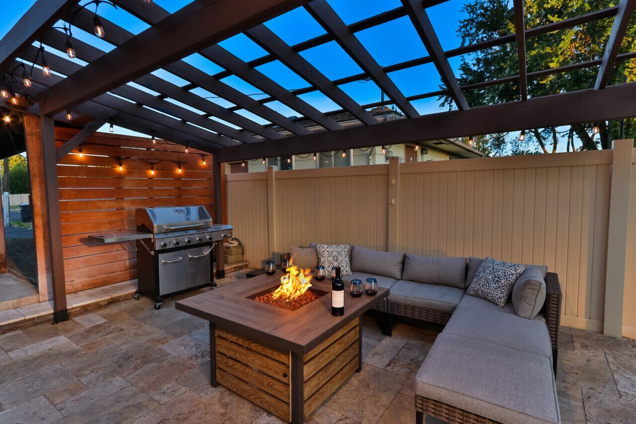 Patio esterno con barbecue, braciere e zona salotto con cuscini.