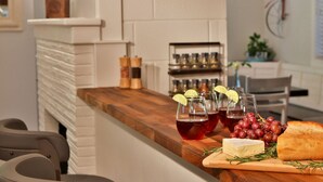 Een bar met een houten toonbank, glazen rode drank, druiven, kaas en een brood.