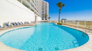 A swimming pool with lounge chairs and a high-rise building in the background. - Beachfront 2BR +Bonus Room @ Lighthouse • Sleeps 8 • Pools & Walk to The Hangout (Gulf Shores)