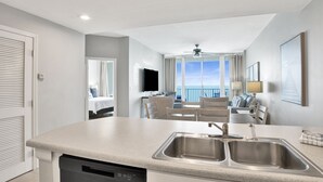 A modern kitchen with a dishwasher, double sink, and a view to a balcony. - Beachfront 2BR +Bonus Room @ Lighthouse • Sleeps 8 • Pools & Walk to The Hangout (Gulf Shores)