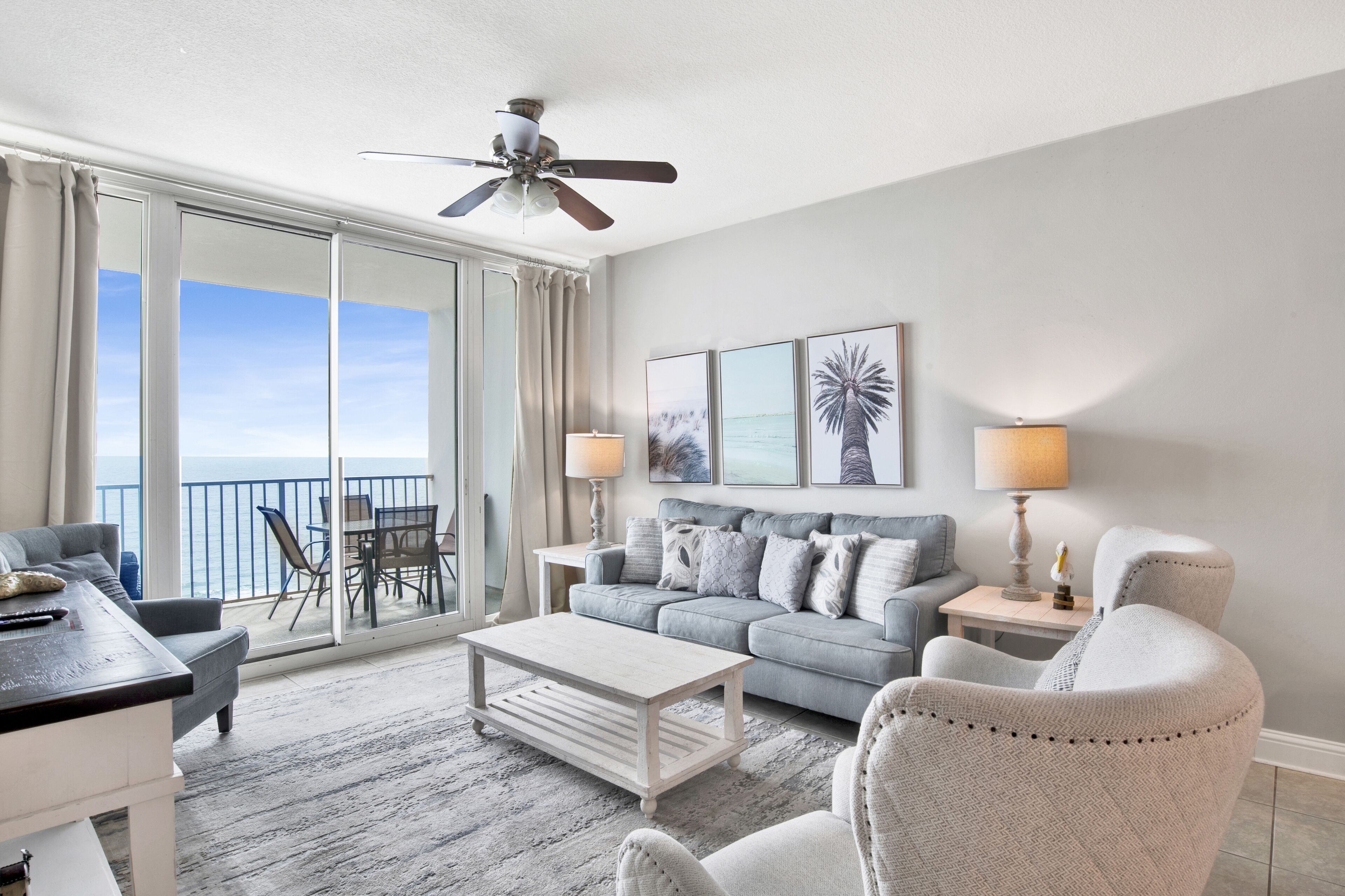 Ein geräumiges Wohnzimmer mit Balkon, Deckenventilator und Meerblick.