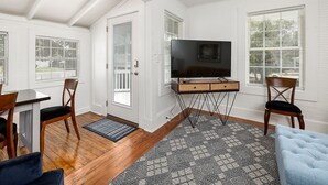 Un espace de vie compact comprenant un téléviseur posé sur un meuble, une table à manger avec des chaises et un tapis à motifs.