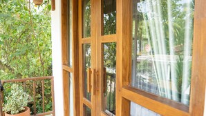 Eine Holztür mit Schieberiegel, die zu einem Balkon mit Terrakottafliesen führt.