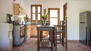 Eine Küche mit Holzschränken, einem Esstisch, Stühlen, einem Kühlschrank und einer Kaffeemaschine.