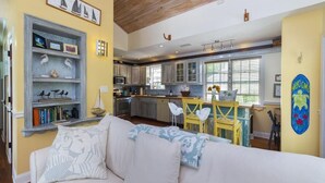 A spacious living area with a sofa, a bookshelf, and a kitchen in the background.