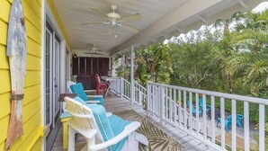 A covered porch with white railings, a ceiling fan, and outdoor seating.