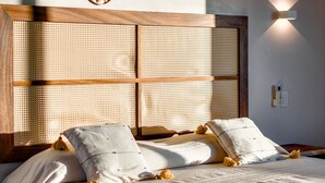 Un dormitorio con una cama grande, un cabecero tejido y decoraciones tejidas en la pared.