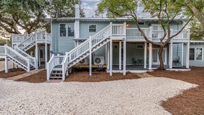 A two-story house with a front porch, a staircase, and a covered outdoor seating area.