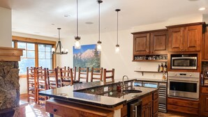 Une cuisine moderne avec des armoires en bois, un îlot central, un four encastré et un mur d’accent en pierre.