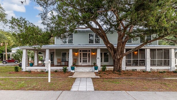 A two-story house with a porch, large windows, and a tree in front. - Beach Cottage with 2 king beds-One short block to beach-Walk to Pier Village! (St. Simons Island)