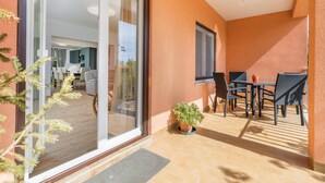 Ein Balkon mit Tisch und Stühlen, einem Blumentopf und einer Schiebetür zu einem Innenraum mit Essbereich.