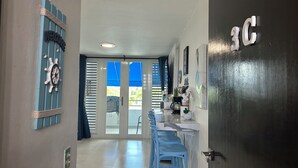 Ein Flur mit einer blauen Tür, auf der "3C" steht, einem Willkommensschild und einer Schiffslenrad-Dekoration.