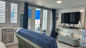 Ein Zimmer mit einem Bett, einem Sofa, einem Fernseher und einem Schild mit der Aufschrift 'Beach House Rules'.