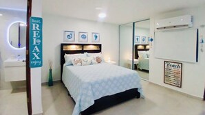Ein Schlafzimmer mit einem Bett, einem Nachttisch, einem Spiegel, einer Wand-Klimaanlage und einem Schild, das Meerblick anzeigt.
