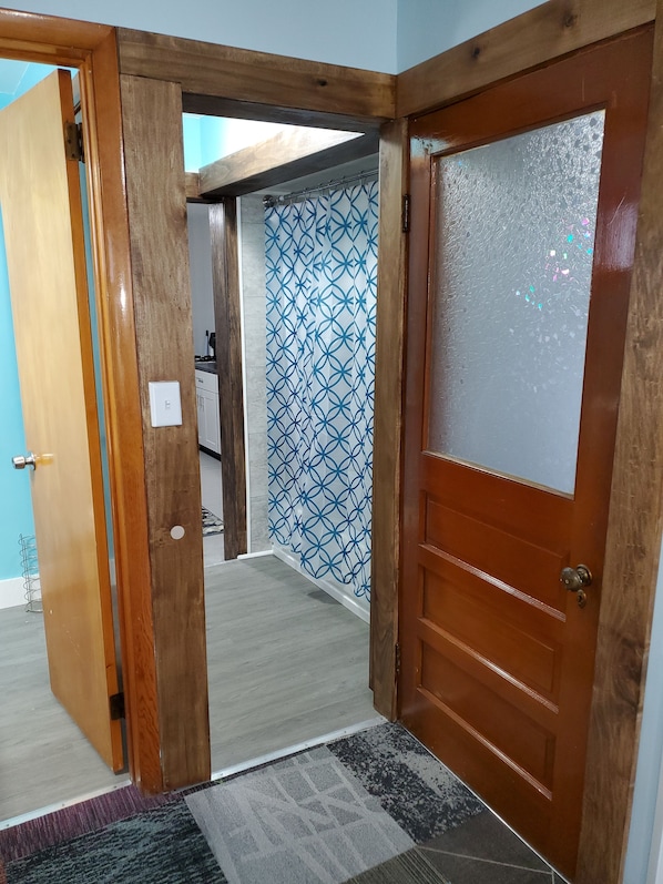 Une porte en bois avec des panneaux en verre dépoli, un mur orné d’un motif et un interrupteur visible.