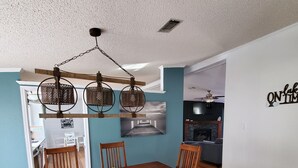 A dining area with a wooden table and chairs, a fruit bowl, and a kitchen in the background. - Beautiful Waterfront  Home on a Private Lake!   (Quinlan)