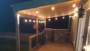 A wooden deck with string lights, a hot tub, and a lantern. - Beautiful Waterfront  Home on a Private Lake!   (Quinlan)
