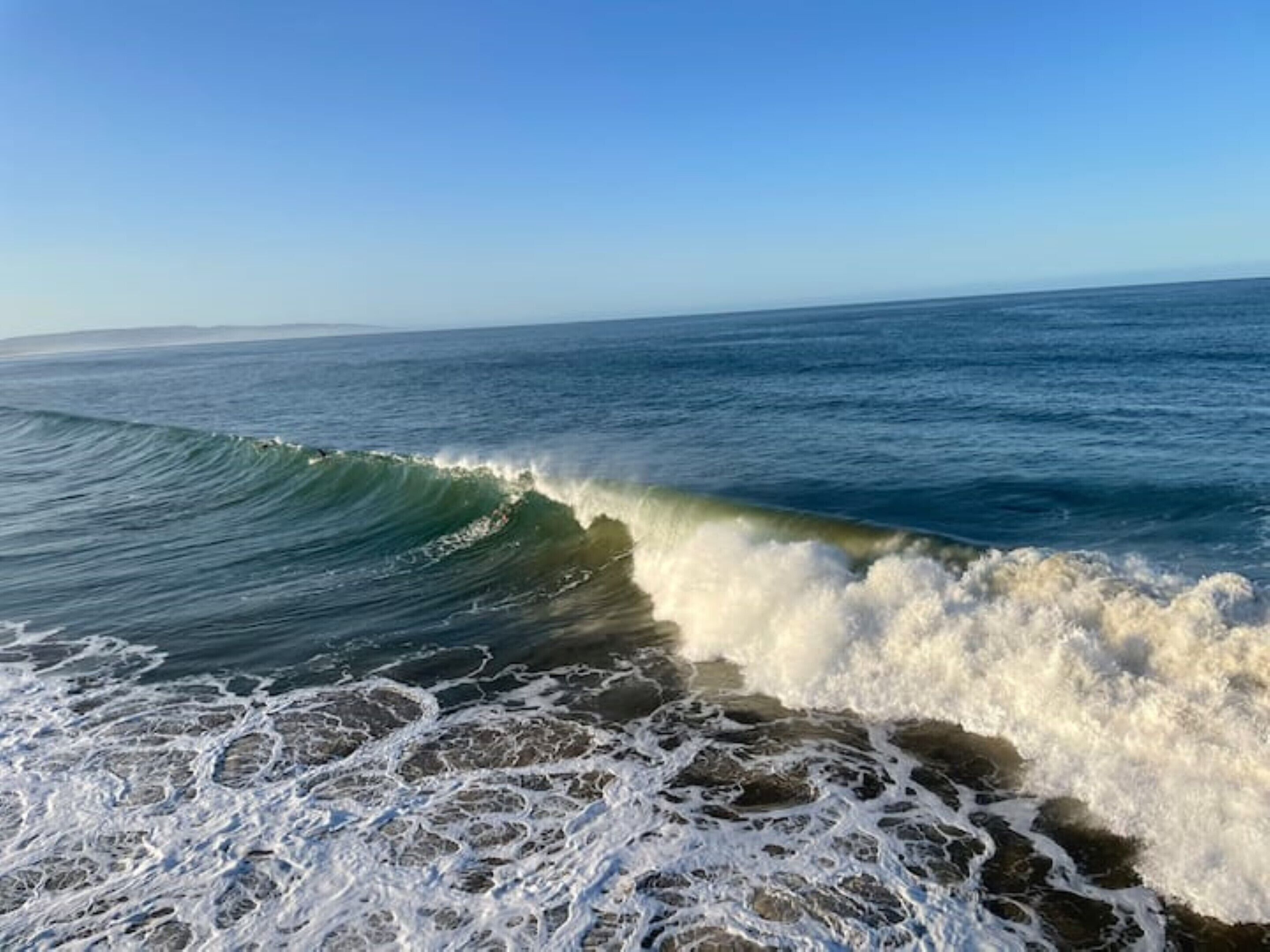 Une vague qui se brise sur une côte rocheuse.